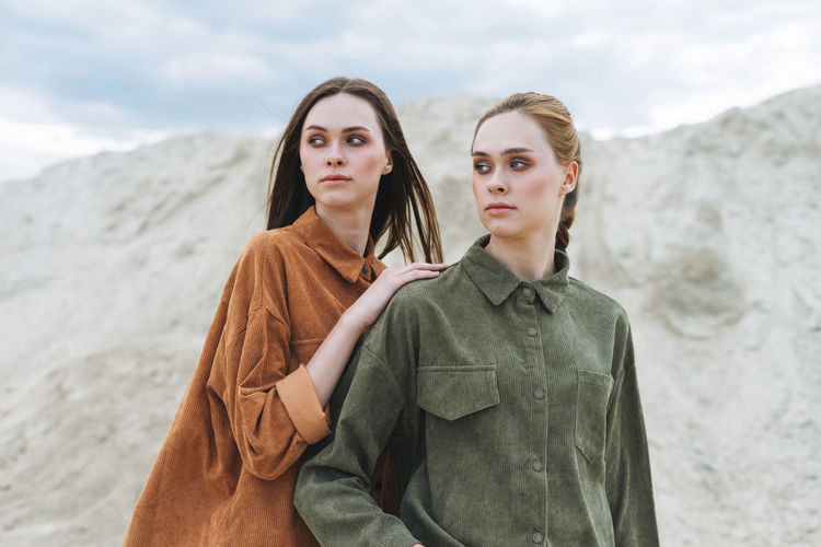 Fashion beauty portrait of young women sisters in brown organic velvet shirts on desert background