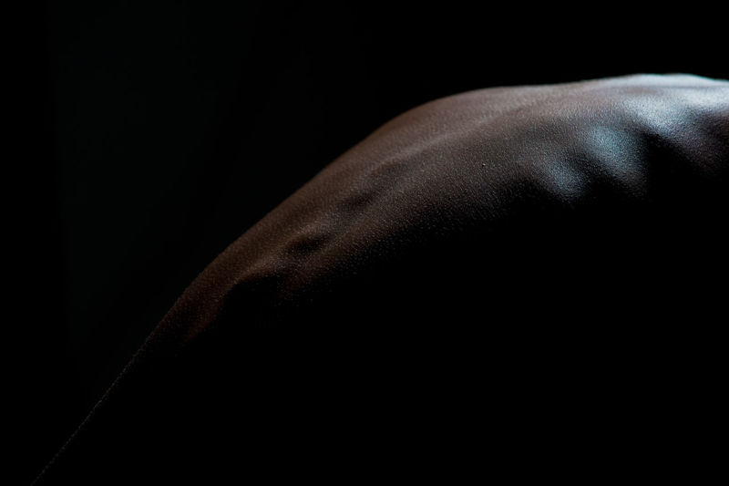 Cropped image of human back against black background