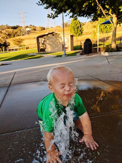 Cute baby boy sitting by fountain