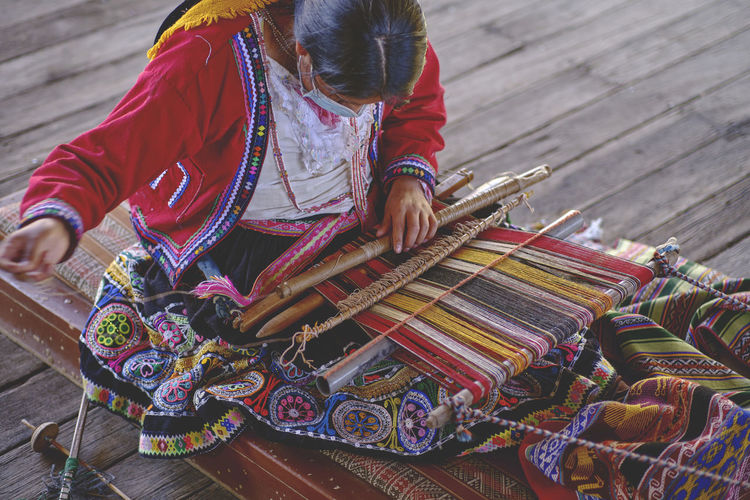 Indigenous woman showing traditional weaving technique and textile making in the andes mountain 