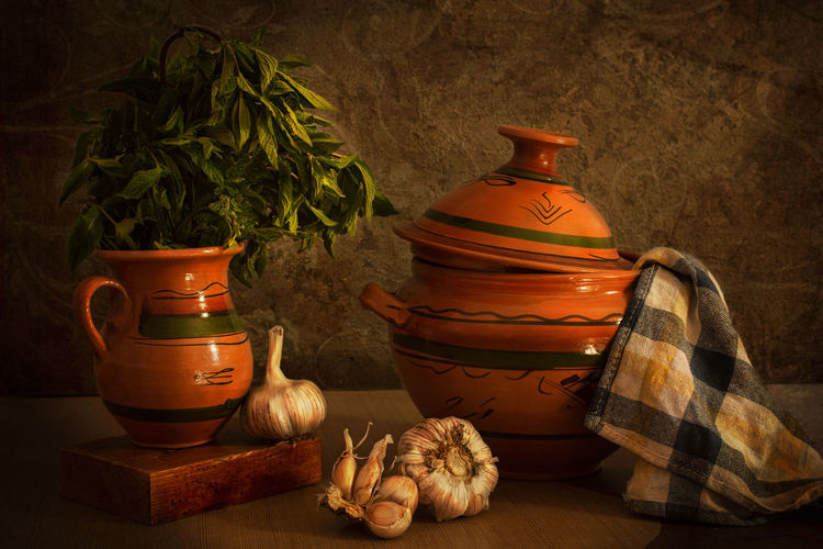 Vintage still life of old jar and garlic and green mint composing a culinary picture .