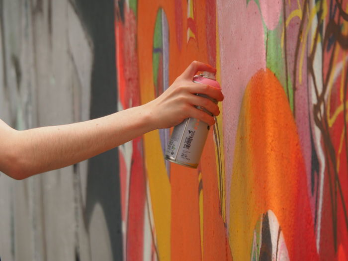 Cropped image of person painting graffiti on wall