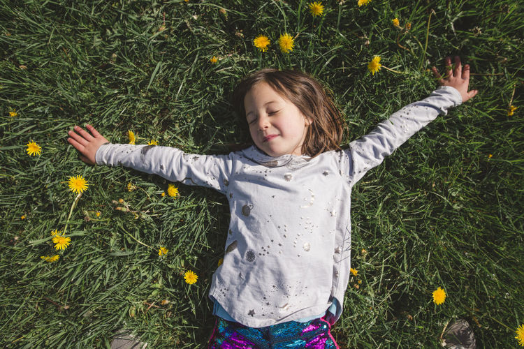 A happy child lays down in a field of wildflowers with closed eyes