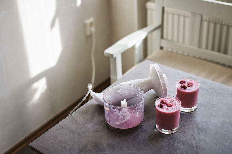 Blender and smoothie in glasses on kitchen table