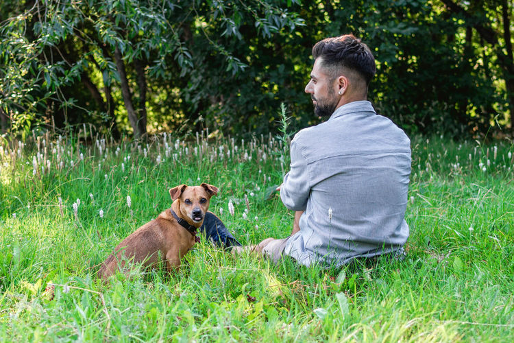 Side view of man with dog on grassy field