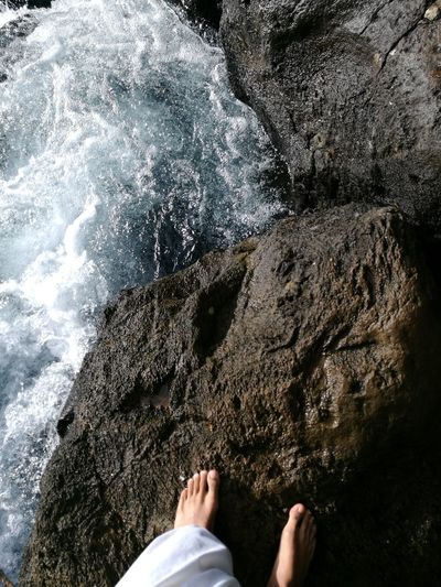 Low section of person on rock by sea