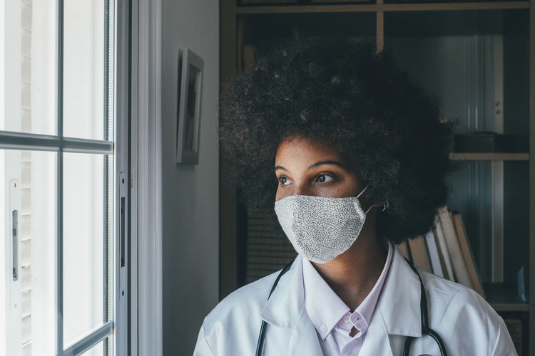 Doctor wearing flu mask looking away at hospital