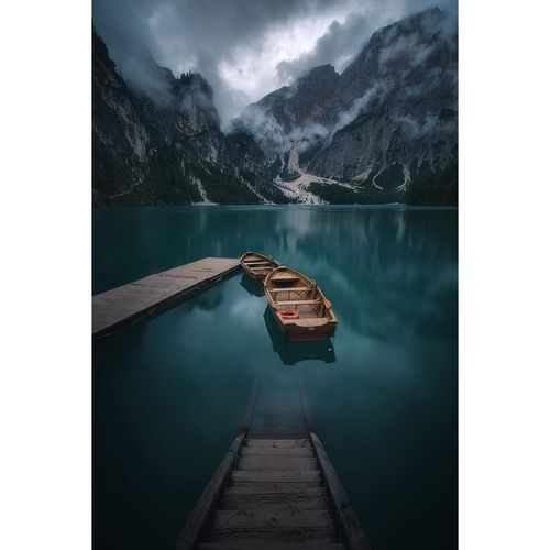 Boats moored on lake against mountains