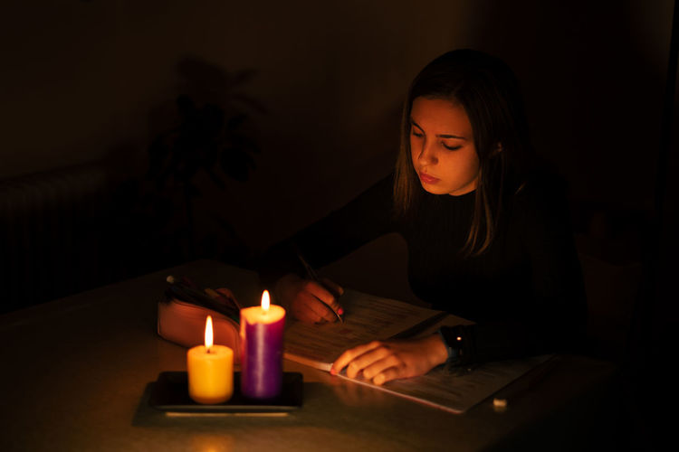 Young woman studying by candlelight. blackout concept, power cut