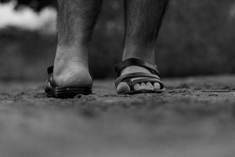Low section of man wearing footwear while standing on ground