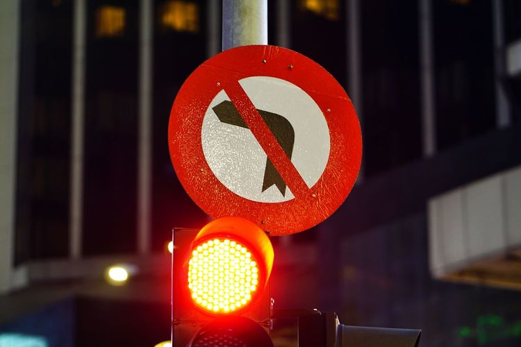 Close-up of arrow sign on road at night