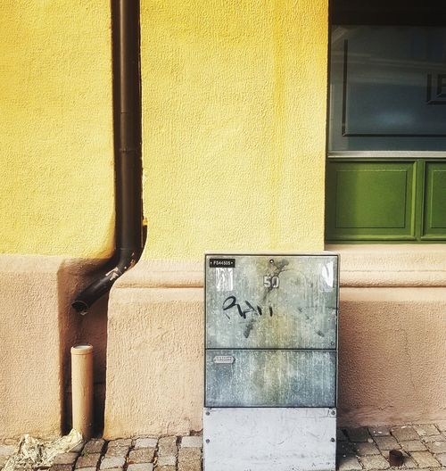 Drainpipe and fusebox against yellow wall