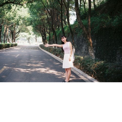 Young woman hailing while standing on road