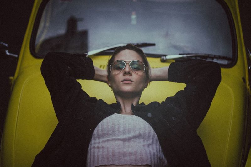 Young woman sitting by yellow car