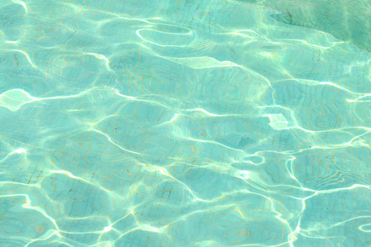 Swimming pool blue water with a wave and sunlight reflection effect