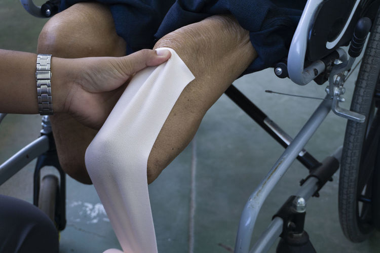 Cropped hand of doctor wrapping bandage on prosthesis leg in hospital