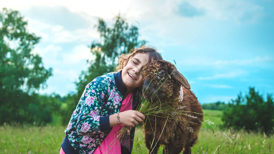 Girl embracing goat in meadow