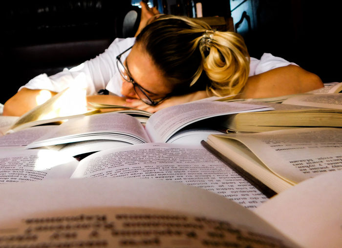 Close-up of young woman resting on books