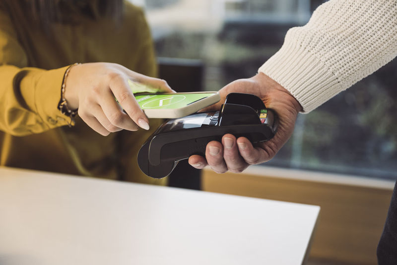Woman paying through mobile phone at cafe