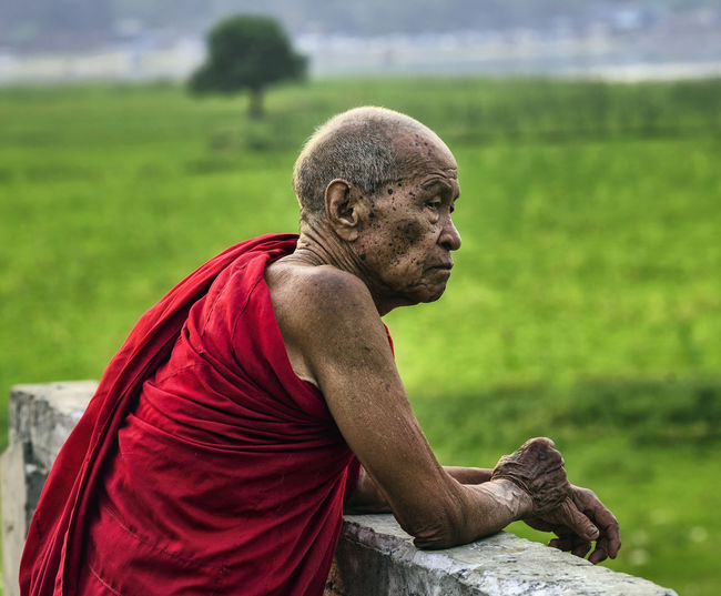Senior monk in traditional clothing standing outdoors