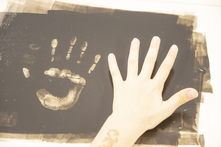Cropped hand of woman with handprint on table