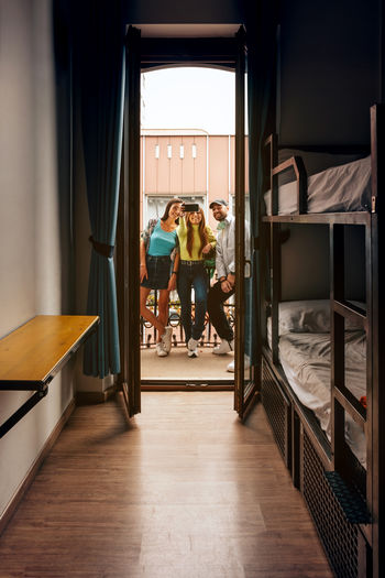 Three young people take a selfie photo with mobile phone on balcony of student room