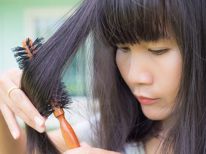 Close-up of woman looking down while brushing hair