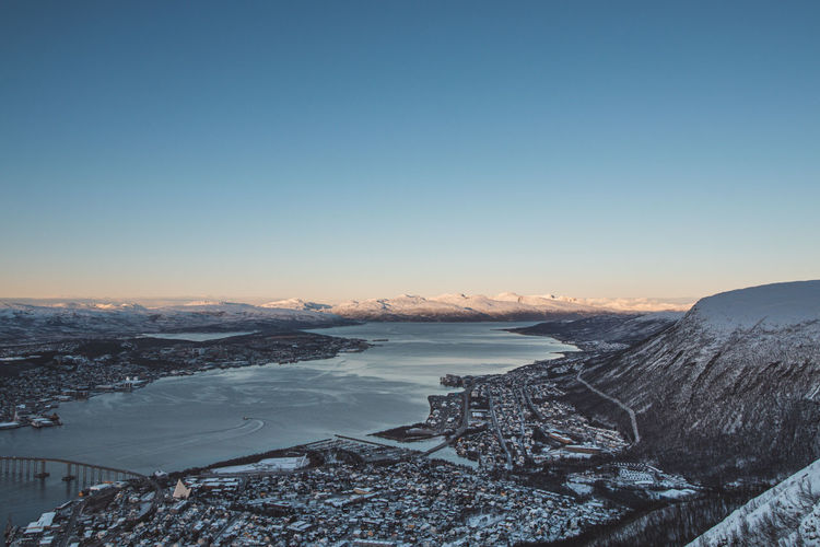 View of the polar town of tromso in northern norway and the snowy hills in background at sunset. 