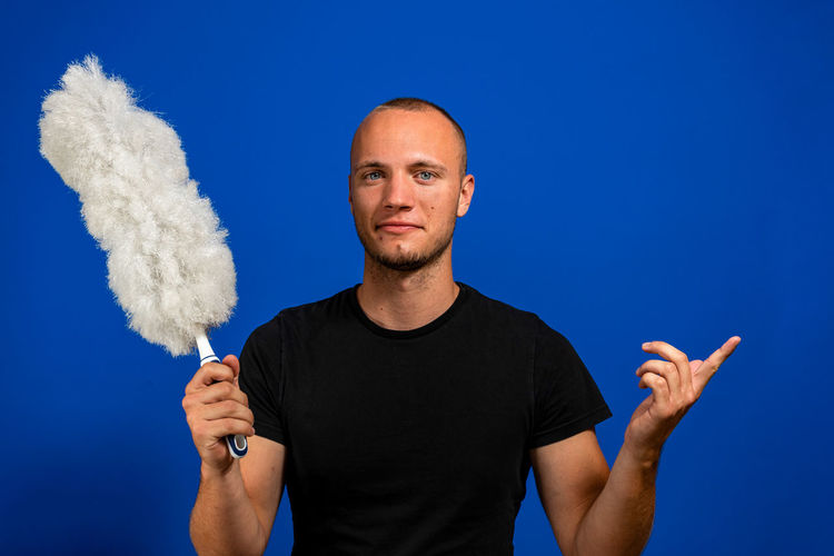 Portrait of young man standing against blue background