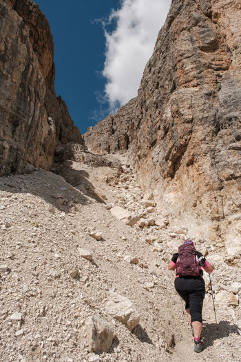 Rear view of woman walking on rock in mountains