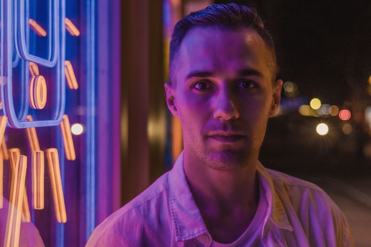 Portrait of young man lit with neon light