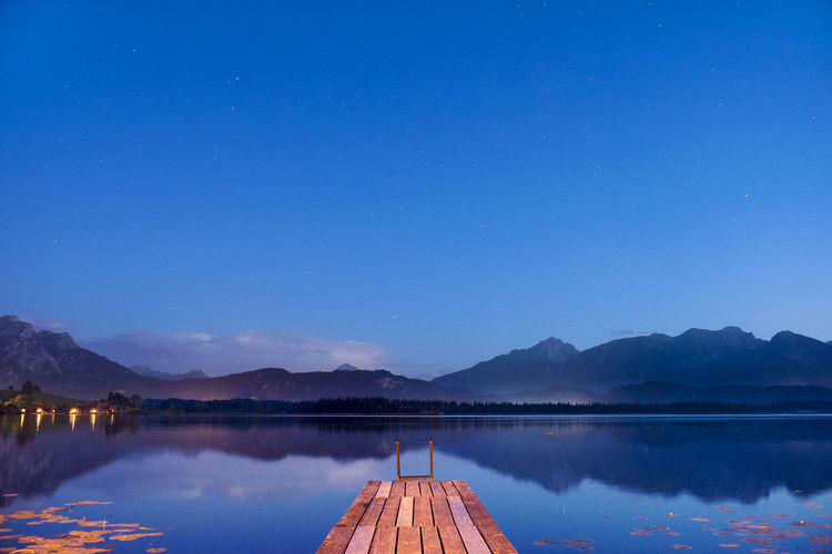 Sunset at lake with mountains and wooden pier in bavaria, germany