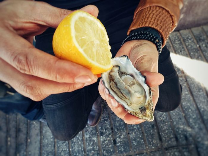 View of a man try to eat fresh oyster with lemon