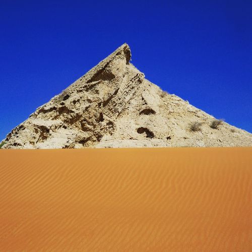 Pyramid at desert against clear blue sky on sunny day