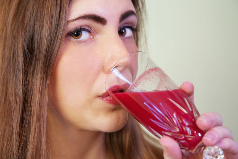 Close-up portrait of a beautiful young woman drinking glass