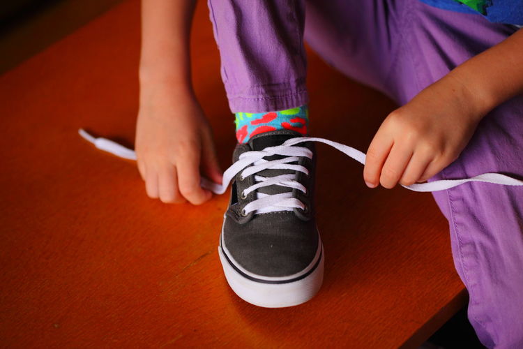 Midsection of girl tying shoelace at home