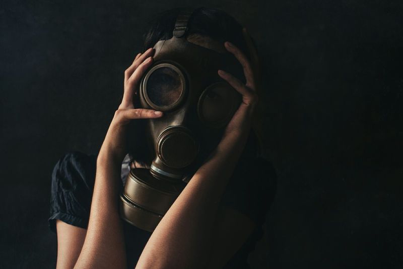 Woman wearing gas mask against black background