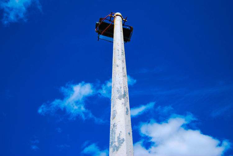 Low angle view of illuminated pole against blue sky