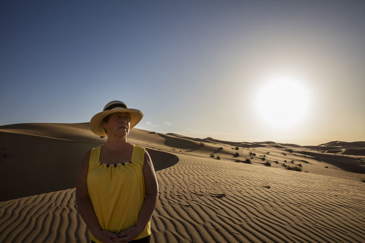 Young woman on sand dune in desert against sky