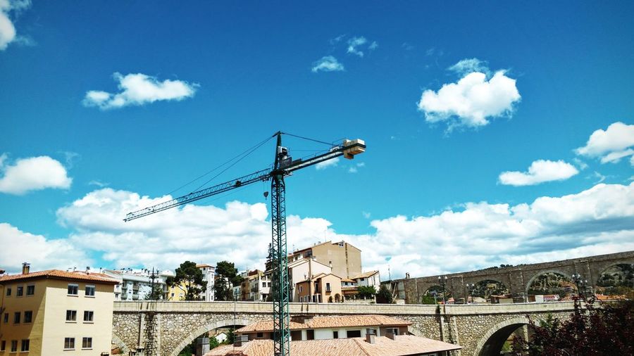 Low angle shot of crane against urban landscape 