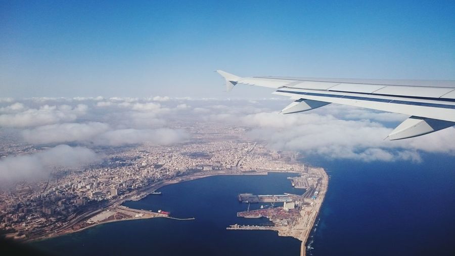 Cropped image of airplane flying over sea against sky