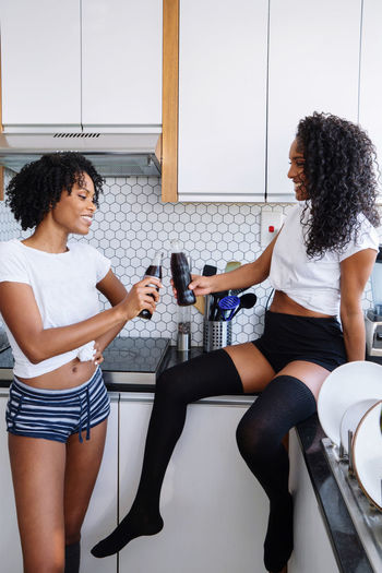 Two black women drinking coca cola in their kitchen