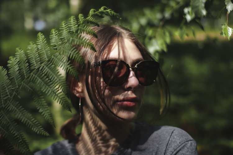 Portrait of young woman wearing sunglasses in forest
