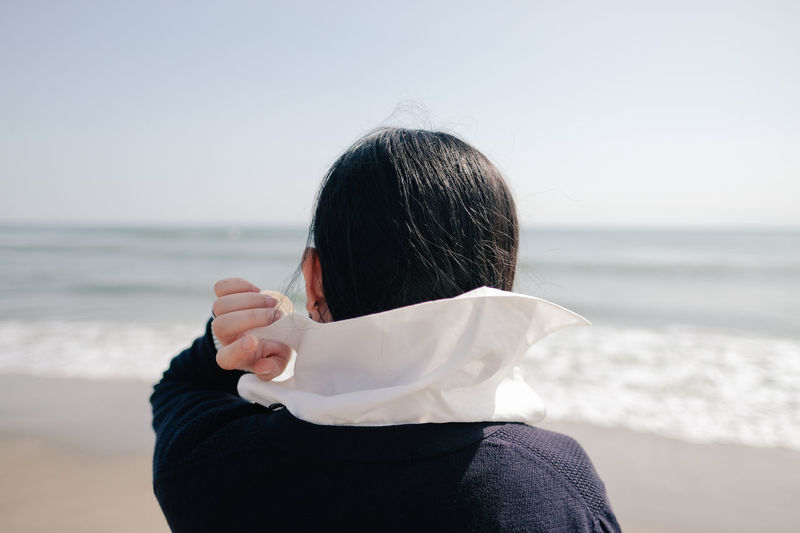 Rear view of woman standing on shore against sea