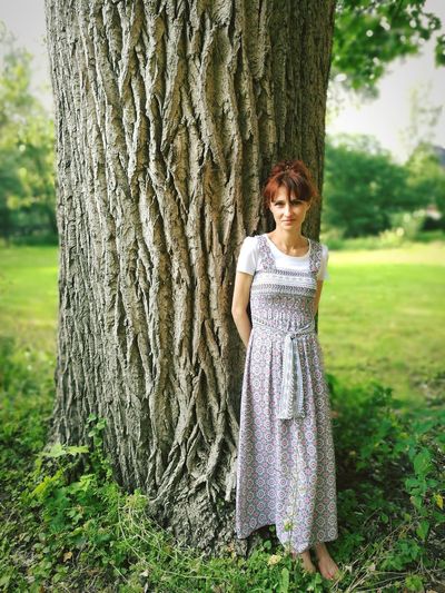 Portrait of teenage girl standing against tree trunk