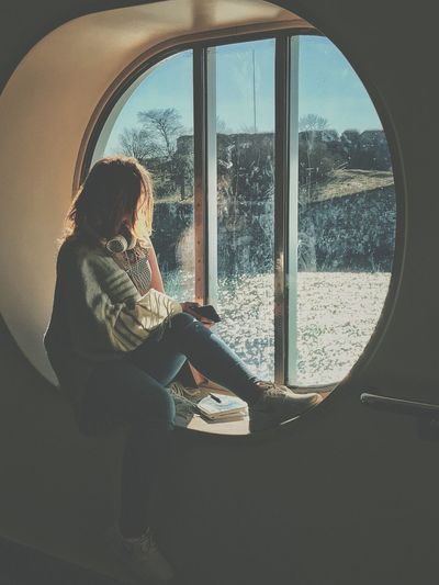 Woman looking through porthole window