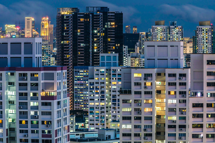 Illuminated modern buildings in city against sky