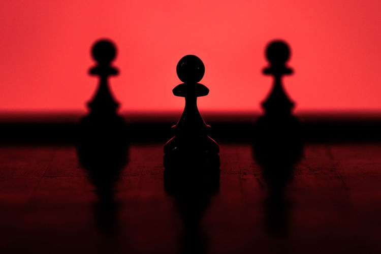Close-up of silhouette chess against red background
