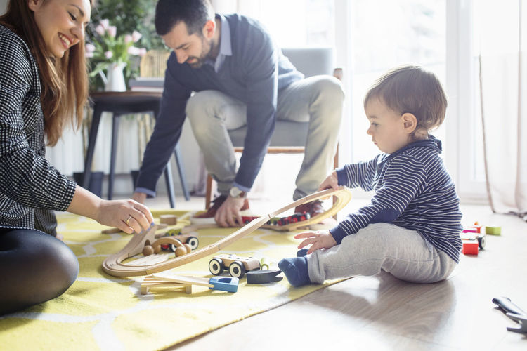 Parents assisting son in making toy railroad track at home