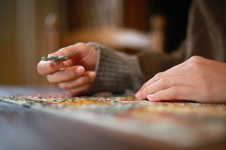Midsection of woman playing puzzle on table